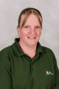 Nursery worker with brown hair wearing green polo shirt.