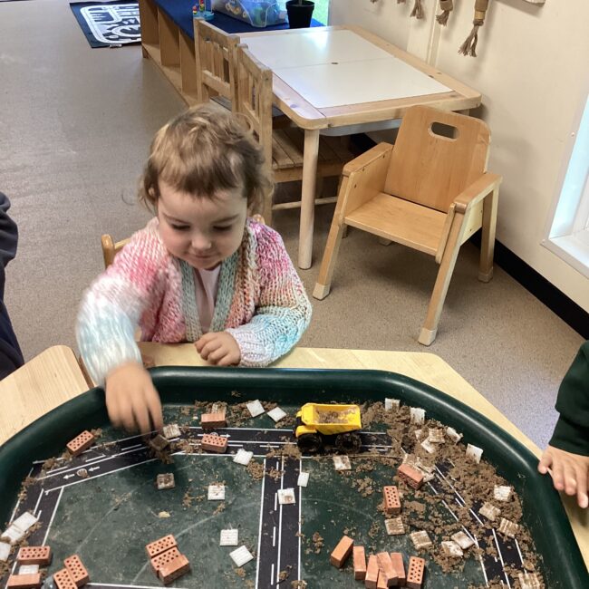 Infant girl doing craft activity on table at nursery.