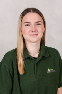 Nursery worker with blonde hair wearing green polo shirt.