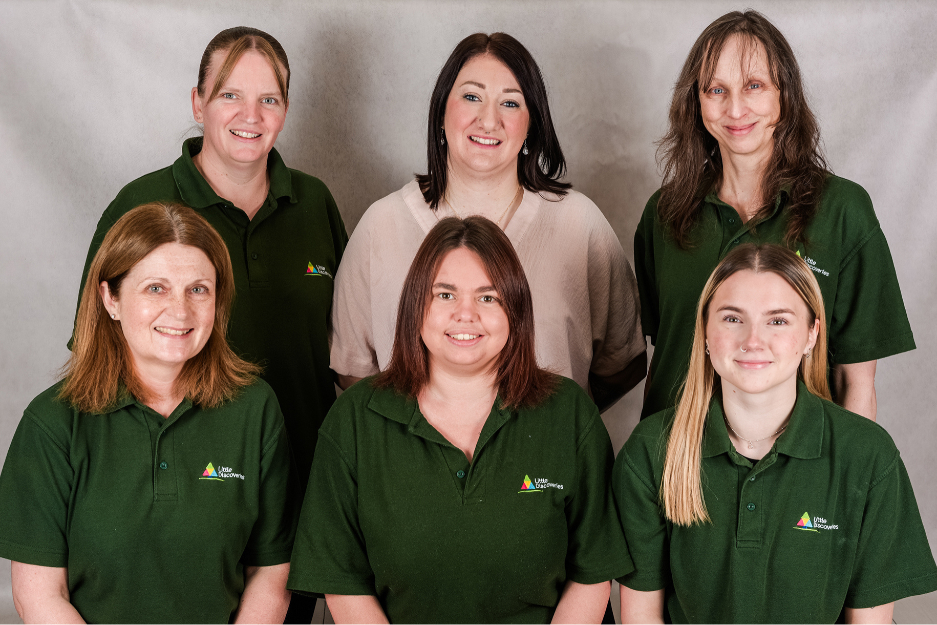 Six female nursery workers smiling in uniform.